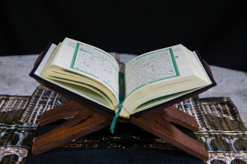 pexels photo 8522578 8522578 An open Quran placed on a wooden stand with visible Arabic calligraphy, symbolizing faith and tradition.